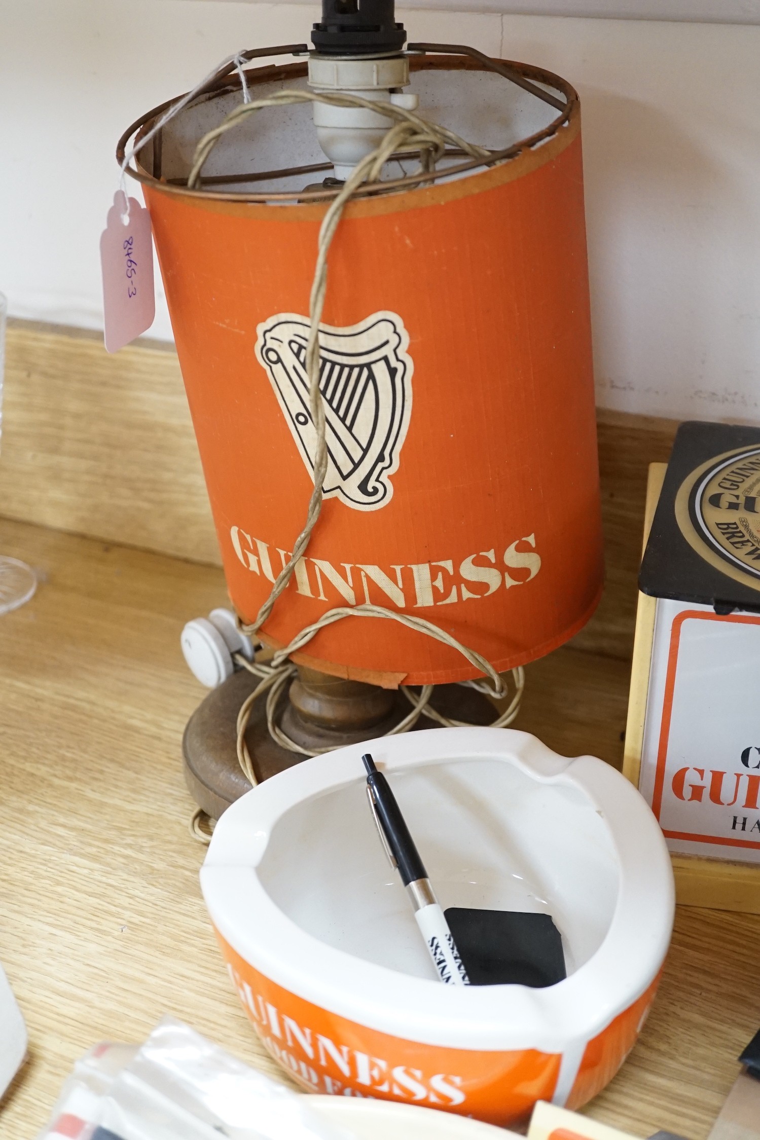 A large quantity Guinness advertising material, including a table lamp with Guinness shade, signage, bar mats, camera etc